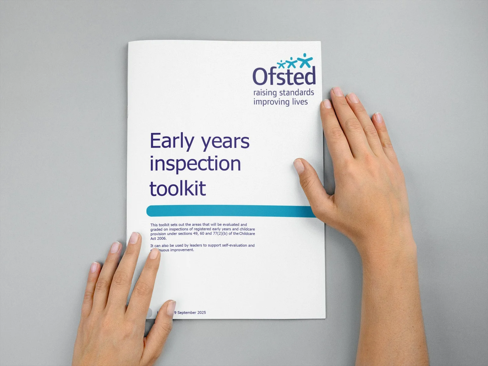 The Ofsted Early Years Inspection Toolkit document held flat by two hands on a grey surface.